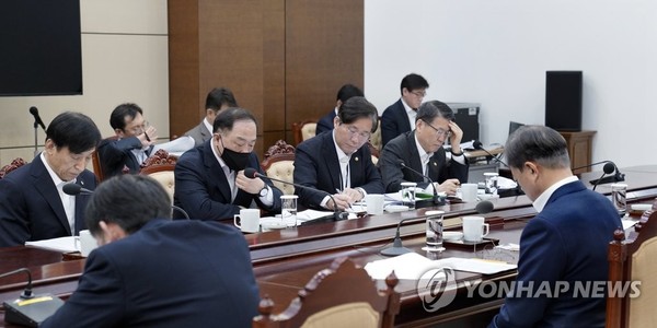 President Moon Jae-in (front, right) receives an emergency briefing from Finance Minister Hong Nam-ki, wearing a face mask, and Bank of Korea Gov. Lee Ju-yeol (back, left) at Cheong Wa Dae on March 13, 2020.