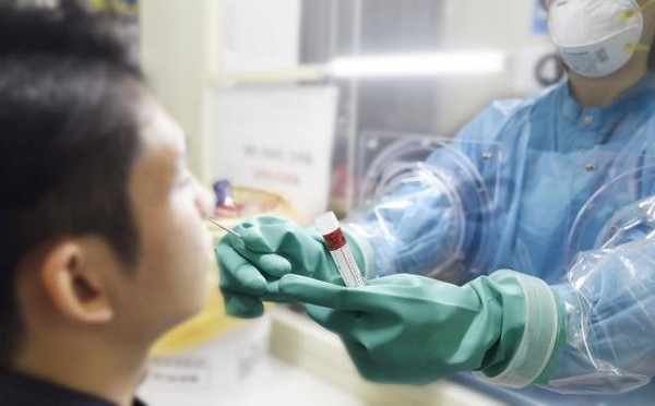 A nurse takes a sample from a man to test for the new coronavirus through a "glove wall" at Boramae Medical Center in Seoul, in this undated photo released by the hospital on March 16, 2020. The medical center has introduced the system, which separates a suspected patient and a medical worker when a COVID-19 virus test is conducted, for the first time in South Korea.
