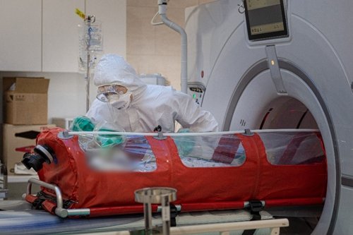 A medical worker talks to a patient, infected with the new coronavirus, in front of a CT scanner room at Catholic University Medical Center in the southeastern city of Daegu on March 13, 2020, in this photo released by the hospital on March 17.