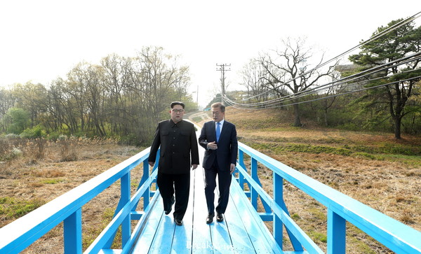 President Moon Jae-in (right) and Chairman Kim Jong-Un of North Korea walk together on the Dobodari Wooden Bridge near Panmunjeom on April 27, 2018.