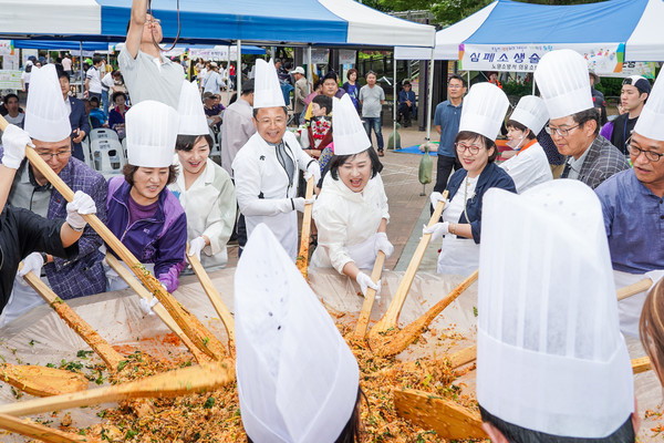 At the 12th Nowon-gu International Day, Chairman Yoonnam Choi (5th from the left) is making bibimbap with the participants.