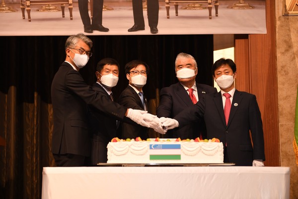 Ambassador Fen (fourth from left) cuts the celebration cake with guests.