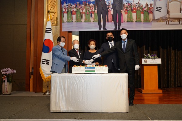 Mrs. Lyumilla Fen (spouse of the ambassador of Uzbekistan), center, cuts the celebration cake with another group of important guests.  Ambassador Ramzi Teymurov of Azerbaijan is seen fourth from left, representing the Seoul Diplomatic Corps.