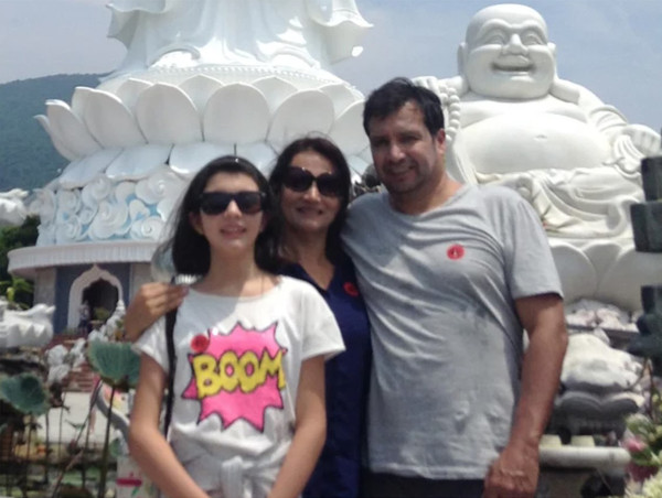 CDA and Mrs. Ossio Bustillos with their daughter, Miss Raquel Otero, in front of the image of Buddhist sculptural works.