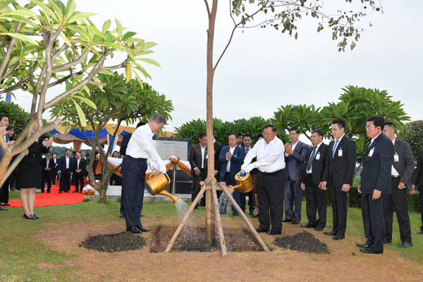 President Moon Jae-in of Korea (left, foreground) and President Bounnhang Vorachith of Laos (opposite President Moon) jointly water a commemoration tree planted in Laos while ranking officials of the two countries look on.