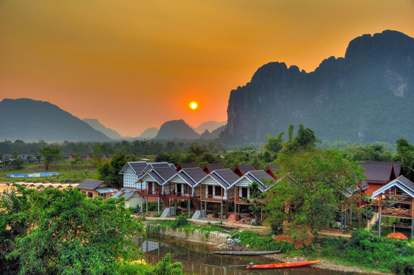 Elevated houses in scenic healing spots with high mountains surrounding in the backdrop, Vangvieng District.