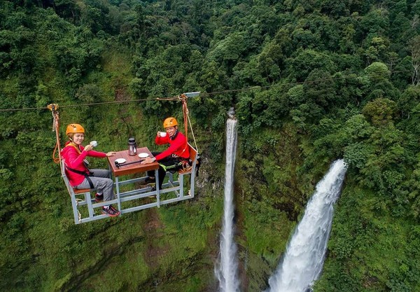 International tourists enjoy a cup of coffee while riding a cable car in the morning, at Farn waterfall, Paksong District, Champasak Province.