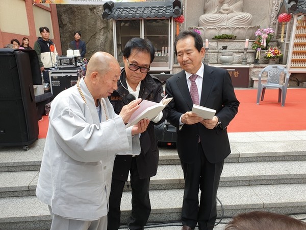 Photo shows Ven. Hongpa (left) introducing his temple to Prime Minister Jeong Sye-gyun (right) and Popular singer Cho Young-nam.