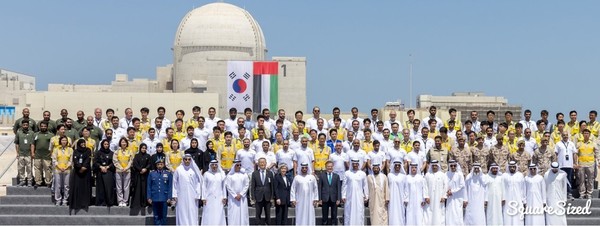 President Moon Jae-in (eighth from left, front row) takes a photo with construction workers and UAE officials at the nuclear power plant in Baraka in March 2018.