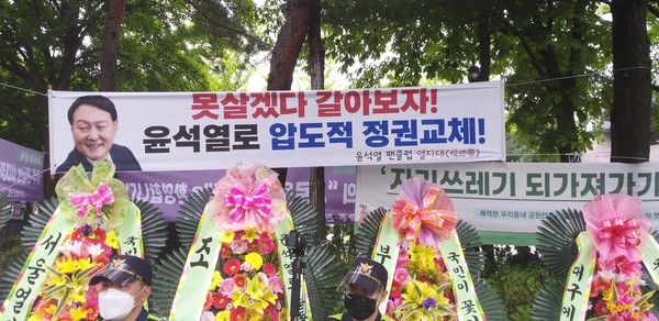 A placard from the Yoon Seok-yeol fan club and a number of wreaths supporting Yoon are placed on the street.