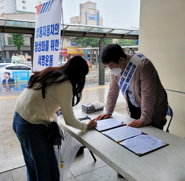 Pyeongtaek University Alumni Association Chairman Kim Soo-woo(right) receives signature from a student in a campaign to save Ssangyong Motor.
