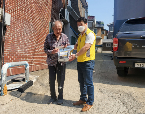Brain City CEO Kim Soo-woo(right) presents goods to a senior citizen in need.