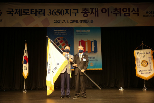 Seo Chang-woo (left), chairman of Papa John’s Korea, who took office as governor of the Rotary International District 3650, takes over the flag from Yoo Jang-hee, former governor, at the inauguration ceremony held at the Grand Hyatt Seoul Hotel in Yongsan-gu, Seoul on July 1.