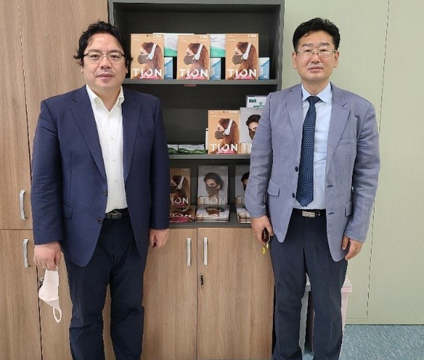 JC Global CEO Kim Gyeong-rea (right) and Korea Post Deputy Managing Editor Sung Jung-wook pose for the camera in front of the 'Tion Titanium Mask' that is said to be very effective for sterilization.