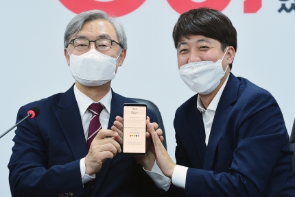 Choi Jae-hyung (left), former head of the Board of Audit and Inspection, holds up his cell phone with Lee Joon-seok, leader of the People Power Party, after filling out a mobile application form at the main opposition party in Yeouido, Seoul, on July 15.