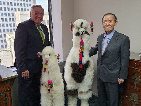Ambassador Matute-Mejia of Peru (left) and Publisher & Chairman Lee Kyung-sik of The Korea Post pose for the camera with traditional dolls of Lama of Peru.