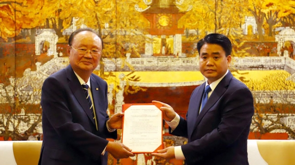 Chairman Lee Dae-bong of Charm VIT Group (left) receives a written permission for construction of Vietnam's first racecourse from Mayor Nguyen Duc Chung of Hanoi City on Oct. 14, 2019.