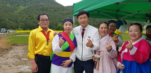 Governor Kim Cheol-woo of Boseong-gun (third from left), Chairman Seo Jeong-mi (fourth from left) and troupe members take a commemorative photo at the Canola Flower Festival in Deuknyang-myeon, Boseong-gun.