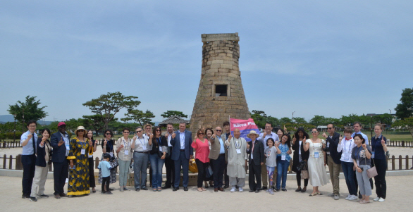 Visiting members of the Seoul Diplomatic Corps pose in front of Cheomseong-dae, a stone meteorological observatory tower in Gyeongju. Chief Abbot Park Seung-eok who invited the ambassadors and other diplomats waves the Flag of The Korea Post.