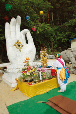 A traditional Korean folk art dancer offers prayers before a Buddhist Hand Sign at the Cheonman-sa Buddhist Temple.