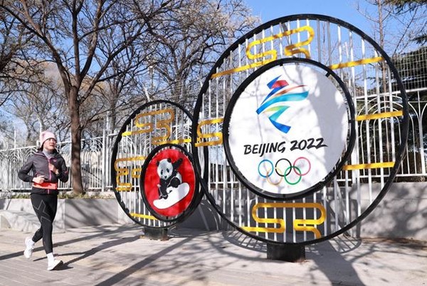 A running enthusiast passes a sign for the 2022 Winter Olympic Games with Chinese characteristics on Aoti Middle Road, Beijing, Nov. 24, 2021. (Photo by Chen Xiaogen/People’s Daily Online)