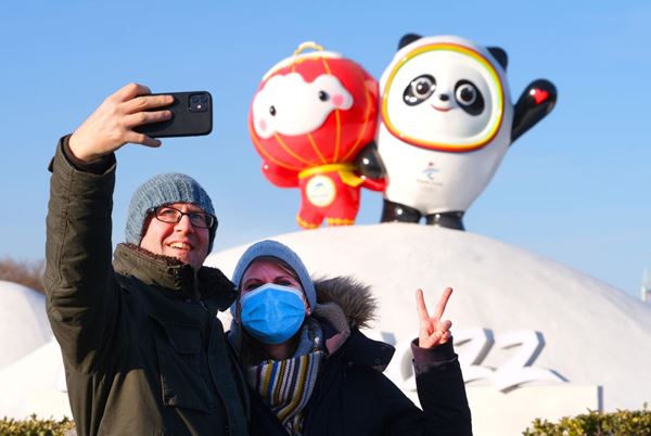 Foreigners take selfies with official mascots of the Beijing 2022 Olympic and Paralympic Winter Games—Bing Dwen Dwen and Shuey Rhon Rhon in Beijing, Jan. 12, 2022. (Photo by Guo Junfeng/People’s Daily Online)