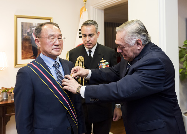Ambassador Mejía of Peru (right) pin a Peruvian Cross of Naval Merit medal on Admiral Boo, former Chief of Naval Operations of the Korean Navy.