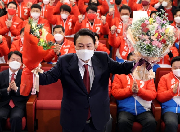 President-elect Yoon Suk-yeol poses for the camera after receiving a bouquet of flowers at the People Power Party’s 20th Presidential Election Counting Room at the National Assembly Library in Yeouido, Seoul on March 10.