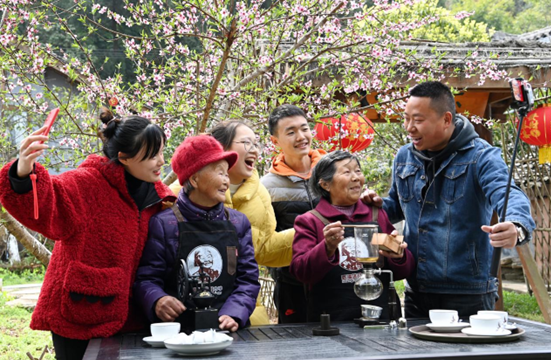 A group of young tourists take photos with two elderly Internet influencers, Wang Suqing and Du Yunzhen, who have been famous on the Internet for running characteristic homestay hotels and making handmade coffee in Wulong village, Langzhong city, southwest China’s Sichuan province, March 4, 2021. (Photo by Wu Xiaorong/People’s Daily Online)