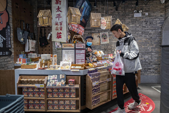 A consumer buys peripheral products of Modern China Tea Shop, an Internet-famous bubble tea chain brand in China, at a shop of the brand in Changsha, capital of central China’s Hunan province, Jan. 2, 2022. (Photo by Wang Chu/People’s Daily Online)