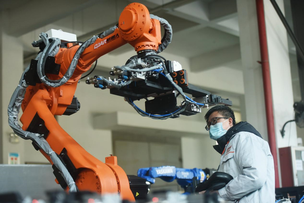 An engineer with Zhejiang Qianjiang Robot Co., Ltd. tests an industrial robot before it rolls off the production line at a workshop of the company located in a robot manufacturing base in Xiaoshan Economic and Technological Development Zone, Hangzhou city, east China’s Zhejiang province, Jan. 17, 2022. (Photo by Long Wei/People’s Daily Online)