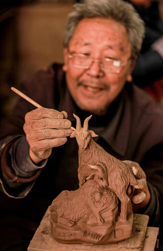 A craftsman makes clay sculpture in the shape of Chinese zodiac sign of sheep in Yangqitun village, Xunxian county, central China’s Henan province. (Photo by Wang Zirui/People’s Daily Online)