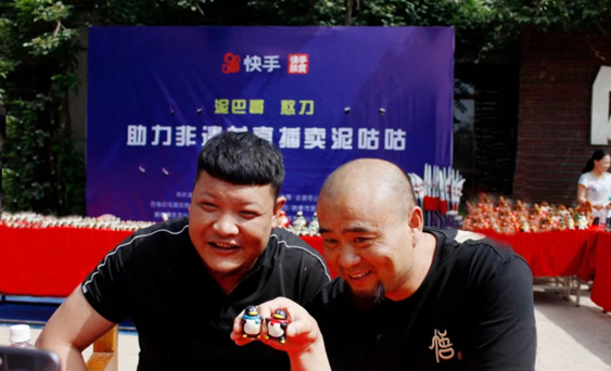 Zhu Fujun (left), a clay sculpture maker in Sixiatou village, Xunxian county, central China’s Henan province, introduces Mud Cuckoos, clay sculptures made with a traditional local handcraft, to netizens via livestreaming. (Photo/www.hebiw.com)