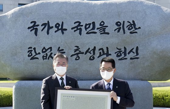 The then President Moon Jae-in (left) presents a copperplate engraved with the revised NIS law to Park Ji-won, the then head of the NIS after Moon finished unveiling the NIS motto-engraved big stone at the NIS on June 4 last year.