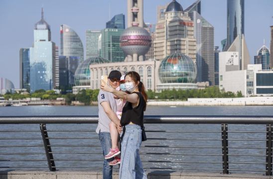 Tourists take selfies at the Bund overlooking the financial district of Lujiazui of Shanghai, June 2, 2022. (Photo by Wang Chu/People’s Daily Online)