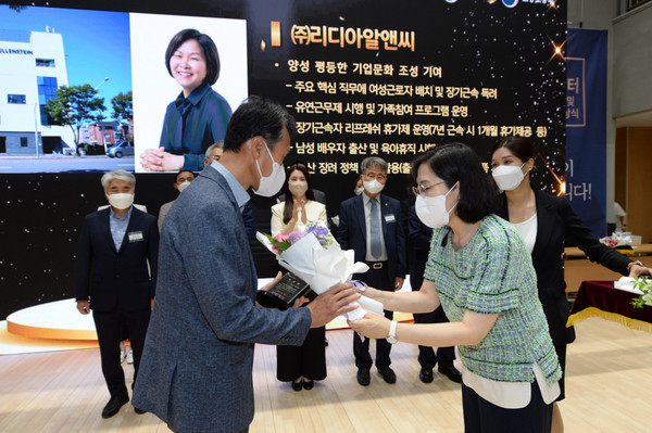 Director Lee Kwang-jin of Lydia R&C (left) is receiving a bouquet of flowers from Minister of Gender Equality and Family Kim Hyun-sook.