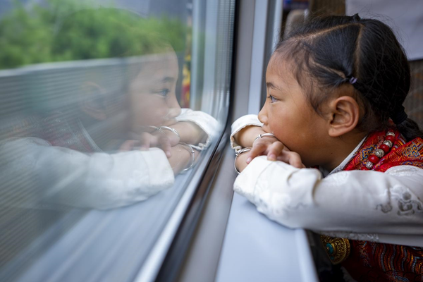 A Tibetan girl looks out a window of a bullet train. (Photo by Xu Yuyao/People's Daily)