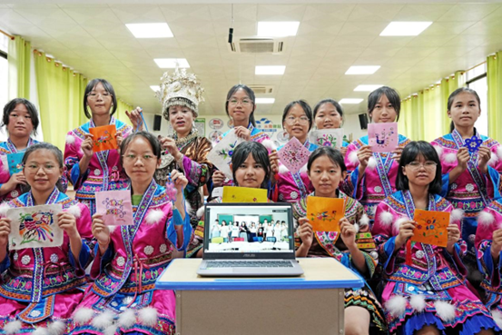 Students from a middle school in Rongshui Miao autonomous county, Liuzhou, south China’s Guangxi Zhuang autonomous region showcase Miao embroidery works with folk artisan Shou Jie (third from left on the second row) on a live class, June 19, 2022. The live class is joined by a group of university students via internet. (Photo by Long Tao/People’s Daily Online)