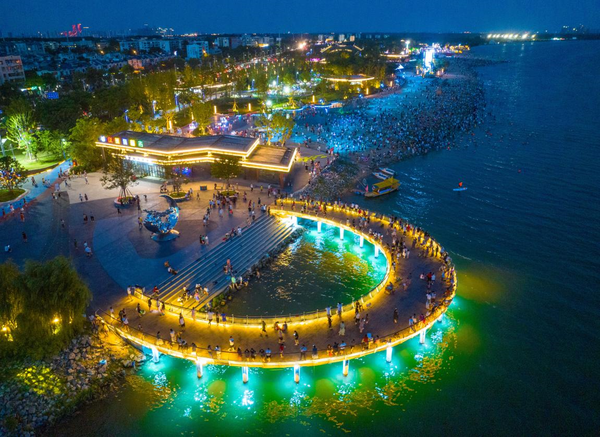 Photo taken on July 10 shows a neon-illuminated beach by the Hanjiang River, Xiangyang, central China's Hubei province. The city of Xiangyang has rolled out a series of measures based on the features of local resources to optimize the night economy. (Photo by Yang Dong/People's Daily Online)