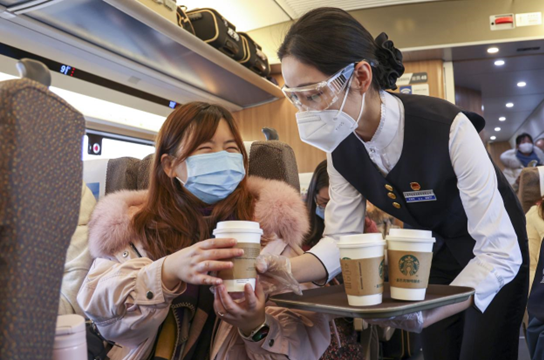 A crew member on train G10 delivers a cup of freshly-ground coffee to a passenger, Jan. 29, 2022. (Photo by Wang Chu/People’s Daily Online)
