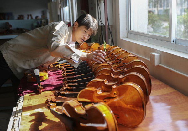 Xu Xiaofeng, a provincial-level artisan, and senior technician and chief violin maker of Finelegend in Huangqiao township, Taixing, east China's Jiangsu province, measures the position of violin sound columns. (Photo by Tang Dehong/People's Daily Online)