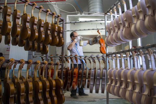A worker of Finelegend in Huangqiao township, Taixing, east China's Jiangsu province spray-paints a violin. (Photo by Tang Dehong/People's Daily Online)