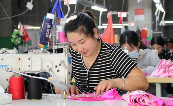Workers of a garment factory work on production lines at a resettlement site in Chengguan township, Shibing county, Qiandongnan Miao and Dong autonomous prefecture, southwest China's Guizhou province, June 14, 2022. (Photo by Tai Shengzhi/People's Daily Online)