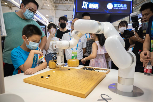 A child plays Go with an artificial intelligence-enabled robot at the 5th Digital China Summit, July 23, 2022. (Photo by Tang Wenjuan/People's Daily Online)