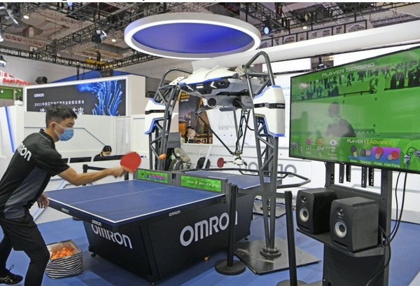 A staff member of Omron plays table tennis with a training machine at the exhibition booth of the Japanese electronics manufacturer at the fourth China International Import Expo, Nov. 6, 2021. (Photo by Chen Bin/People's Daily Online)