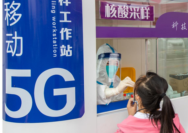 A medical worker collects a swab sample from a girl at a nucleic acid testing site in Jiangdong township, Jinhua, east China's Zhejiang Province, May 16, 2022. The application of a high-speed 5G network has enabled the testing site to have residents' information automatically input into the computer system by scanning their health codes. The whole sampling process for each person can be completed in less than 20 seconds. (Photo by Yang Meiqing/People's Daily Online)