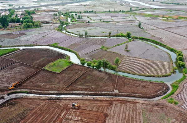 Excavators are leveling farmland in Wujiang township. Ganzhou district, Zhangye, northwest China's Gansu province, May 14, 2021. Ganzhou district has vigorously promoted the construction of high-standard farmland to optimize rural ecology. By providing farmers with water-saving irrigation technologies, farming machines and logistics support, the district has prominently improved the production efficiency of the agricultural sector. (By Yang Yongwei/People's Daily Online)
