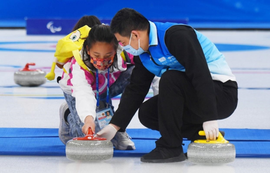 The National Aquatics Center, also known as the "Ice Cube," opens to the public for the first time on April 16, 2022 after the conclusion of the Beijing 2022 Winter Olympics and Paralympics. Photo shows a coach teaching a child to play curling. (Photo by Sun Lijun/People's Daily Online)