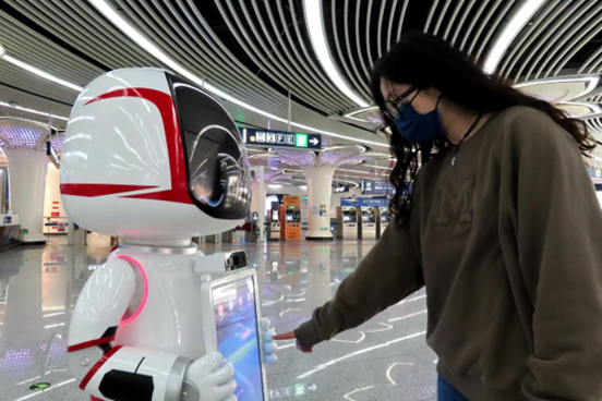 A passenger checks information from a smart service robot at the Caoqiao station of the Daxing Airport Express of the Beijing Subway, April, 10, 2022. (Photo by He Luqi/People's Daily Online)