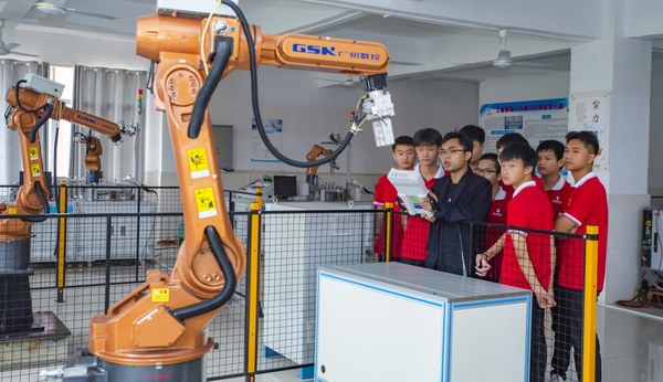 A teacher instructs students to control a robotic arm at a training workshop in Xinyu, east China's Jiangxi province, Oct. 14, 2021. (Photo by Zhao Chunliang/People's Daily Online)